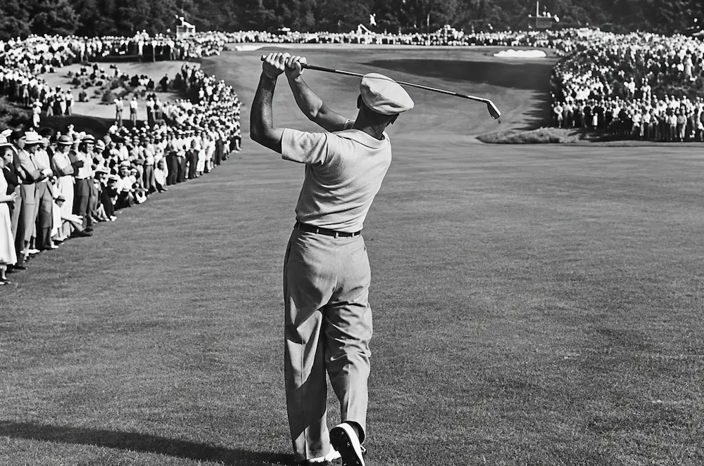 A golfer striking an iron in front of a gallery